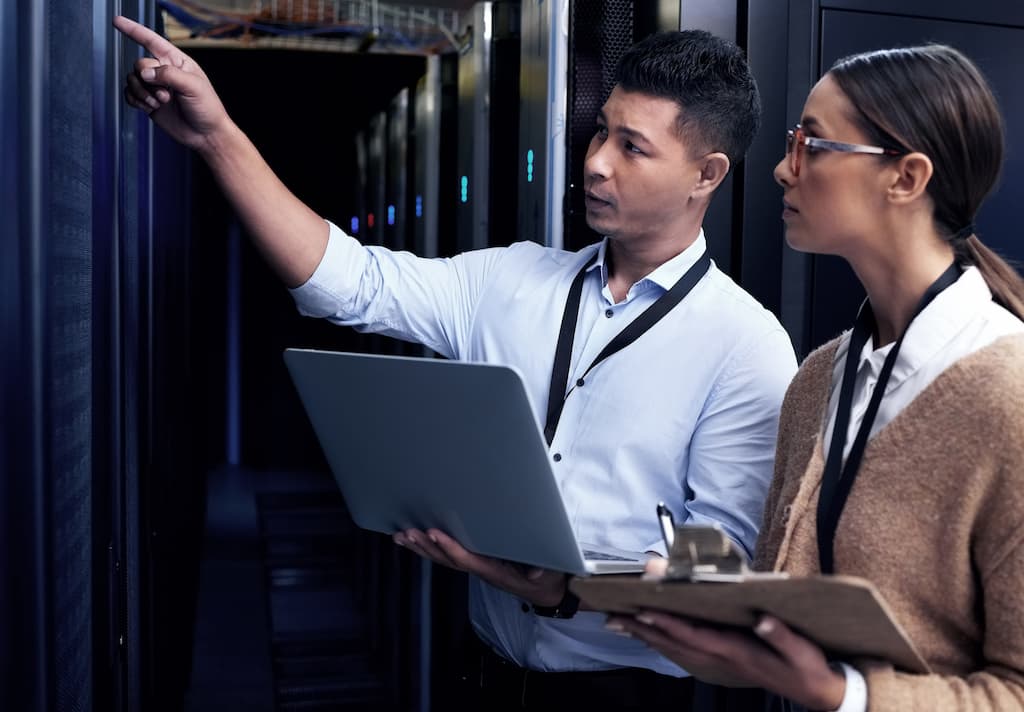 Engineers in server room pointing out benefits of legacy system modernisation