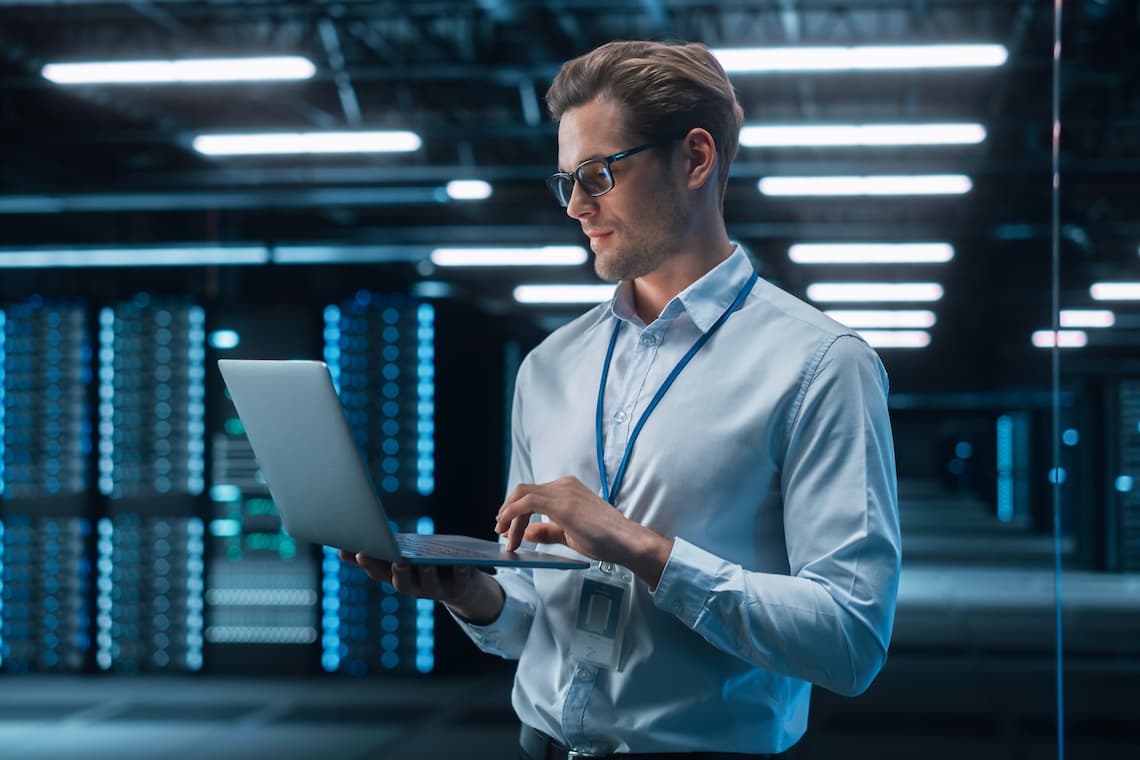 Man in server room on laptop maximising network potential with network management